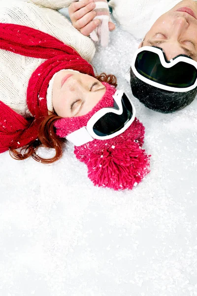 Pareja joven tumbada en la nieve — Foto de Stock