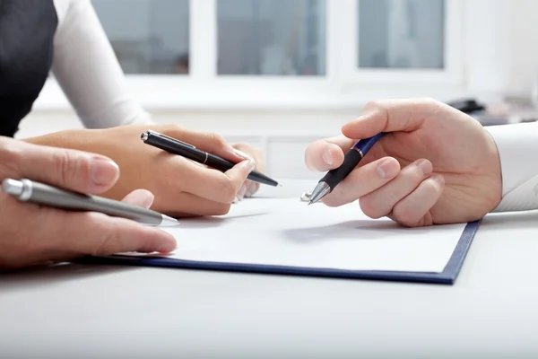 Mãos de empresários segurando canetas sobre documento — Fotografia de Stock