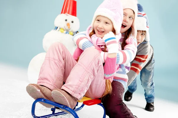 Jongen duwen slee met kleine meisjes — Stockfoto