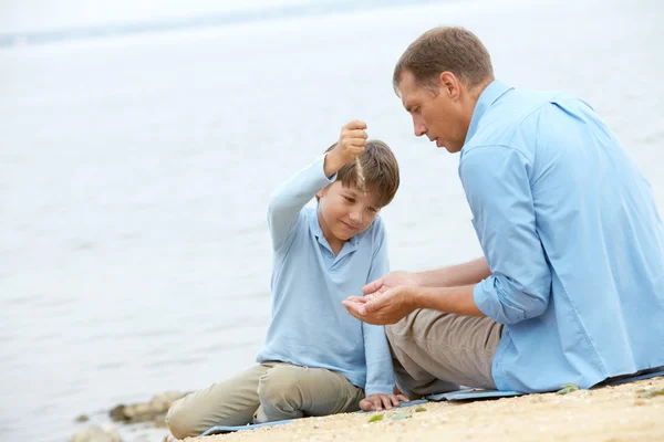 Junge streut seinem Vater Sand in die Hände — Stockfoto