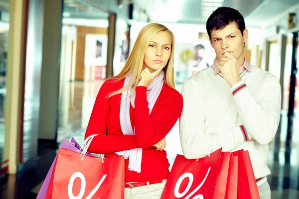 Pareja con bolsas de compras de pie en el escaparate — Foto de Stock