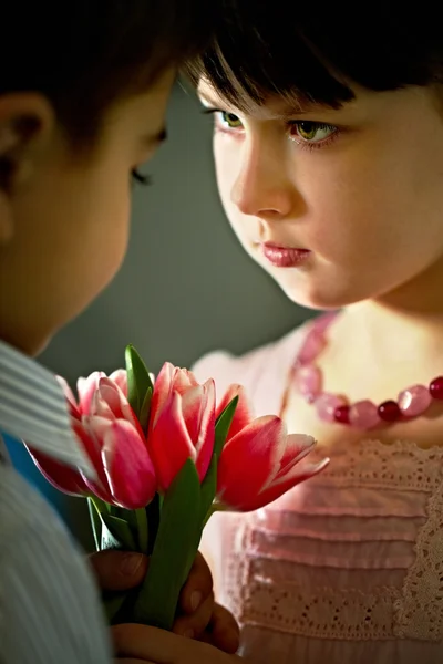 Menina bonita dando flores para menino — Fotografia de Stock
