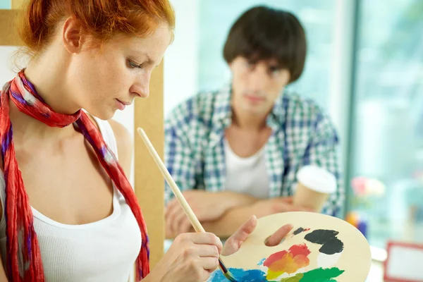 Woman with palette against her sitting model — Stock Photo, Image