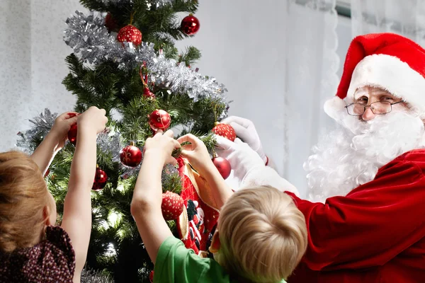 Children with Santa Claus decorating a Christmas tree — ストック写真