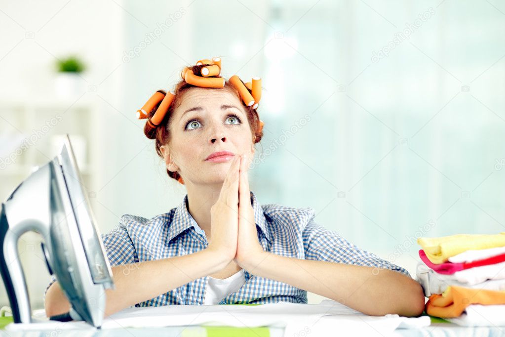 Housewife praying by ironing board in despair