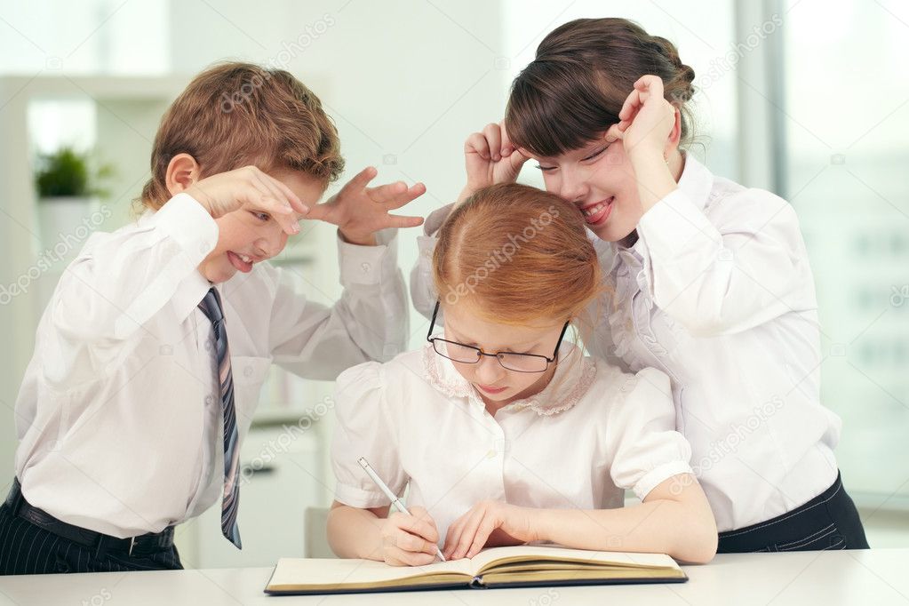 Schoolchildren making faces to a girl nerd