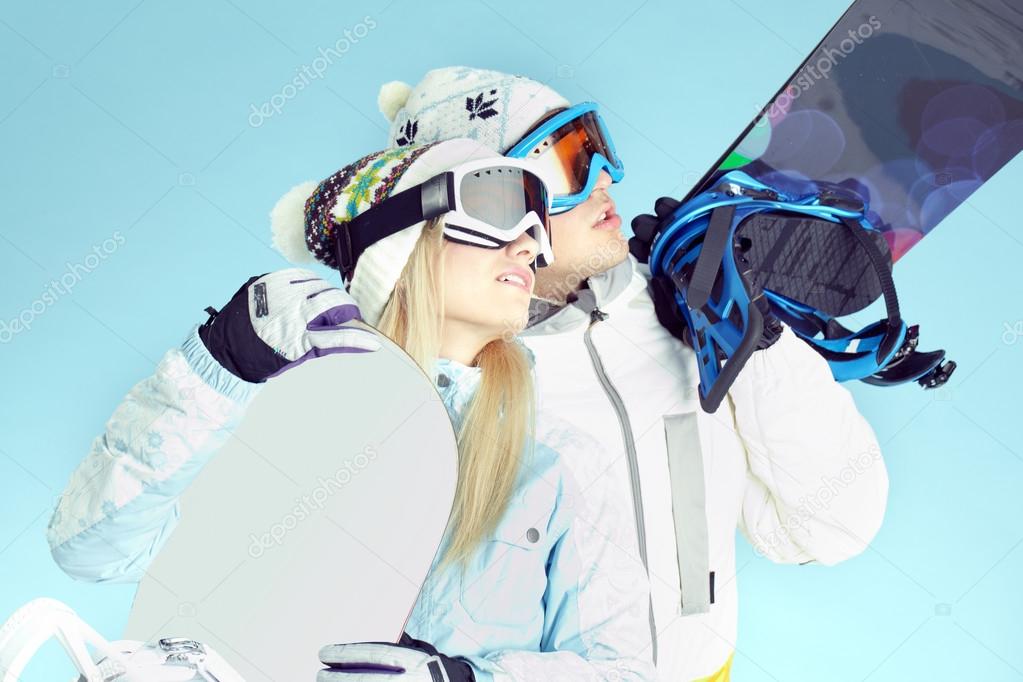 People in ski goggles holding snowboards