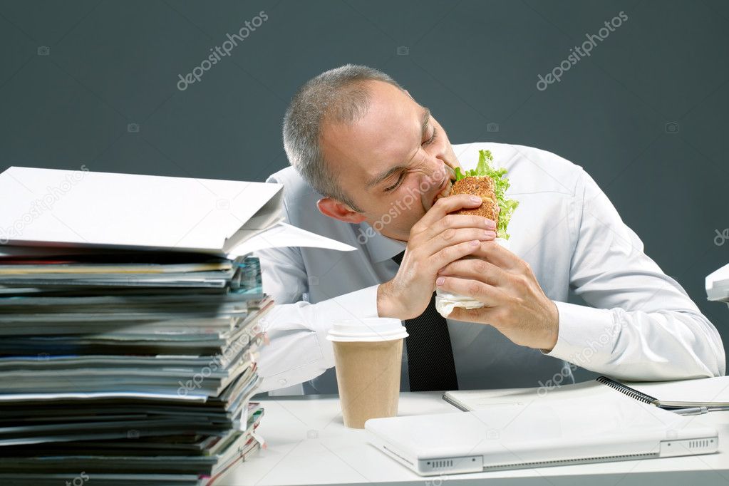 Office worker eating sandwich at his desk