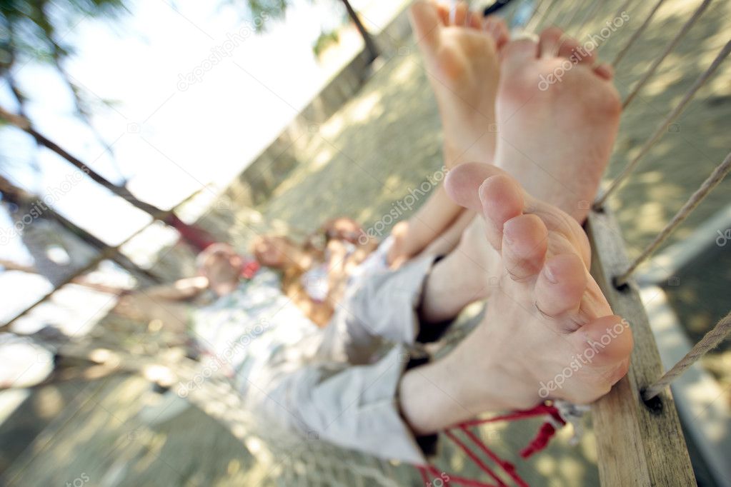 Feet of woman and man relaxing in hammock 