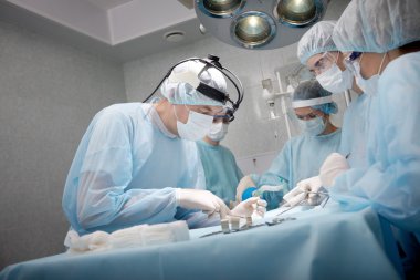 Surgeons saving a patient in operating room  clipart