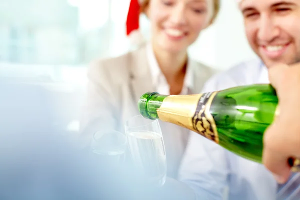 Garrafa derramando champanhe para colegas felizes — Fotografia de Stock