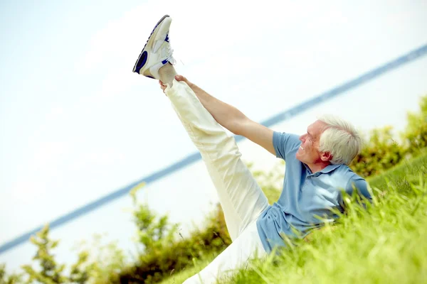 Senior man die zijn been uitstrekt — Stockfoto