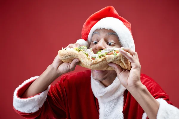 Hungriger Weihnachtsmann beißt Sandwich — Stockfoto