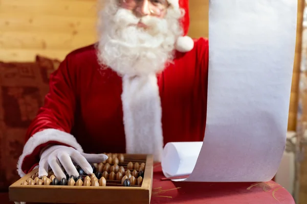 Санта держит свой список подарков и подсчитывает — стоковое фото