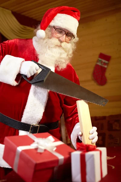 Santa Claus making presents himself — Stockfoto