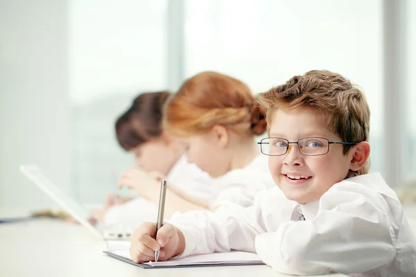 Jongetje glimlachend door zijn klasgenoten — Stockfoto