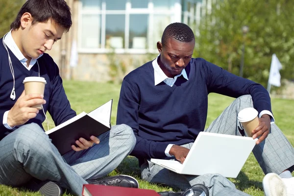 Zwei Studenten lesen für ihre Seminare auf dem Campus — Stockfoto