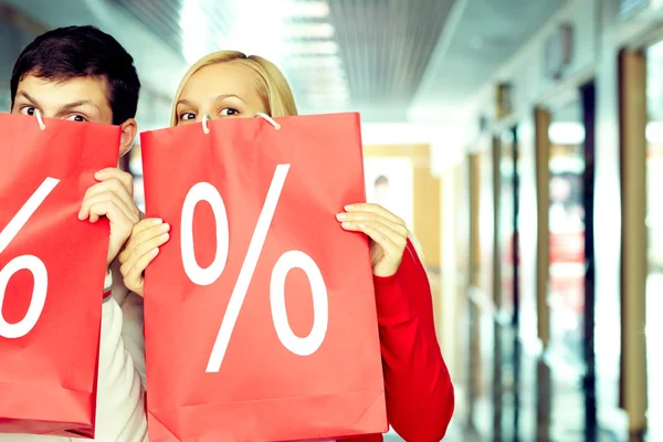 Casal com sinal percentual em sacos de compras — Fotografia de Stock