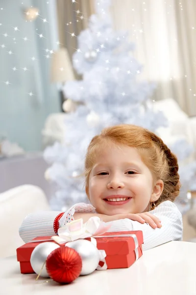 Bambina seduta a tavola con una confezione regalo — Foto Stock