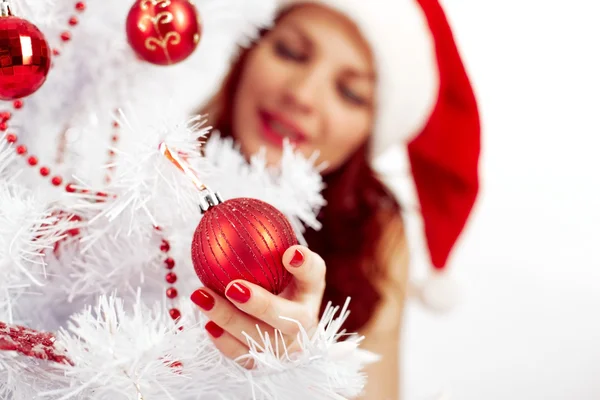 Woman hanging a ball on Christmas tree — Stock fotografie