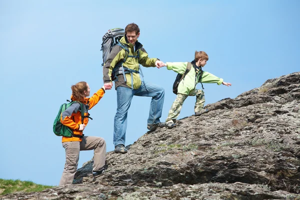 En familj som klättra upp i toppen av ett berg — Stockfoto