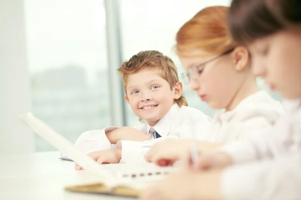 Schooljongen glimlachend onder zijn klasgenoten — Stockfoto