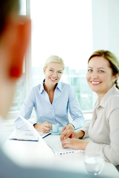 Бізнес-леді слухають свого боса і посміхаються — стокове фото