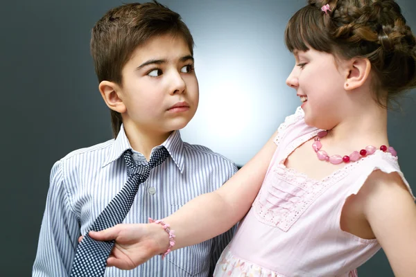 Girl holding tie while boy staring at her — Stockfoto