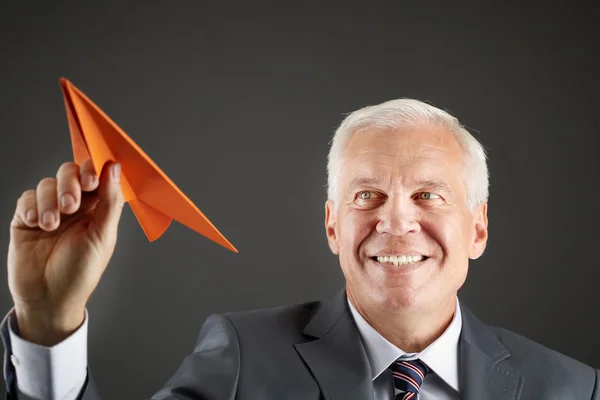 Hombre de negocios senior con avión de papel en la mano — Foto de Stock