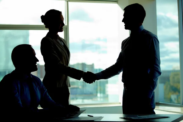 Geschäftsleute beim Händeschütteln im dunklen Büro — Stockfoto