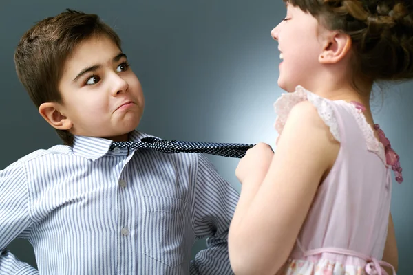 Glückliches Mädchen zieht Krawatte von Junge — Stockfoto