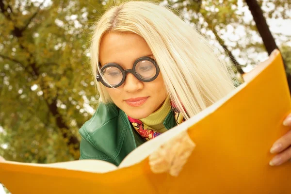 Girl in funny glasses reading a book — Stock Photo, Image