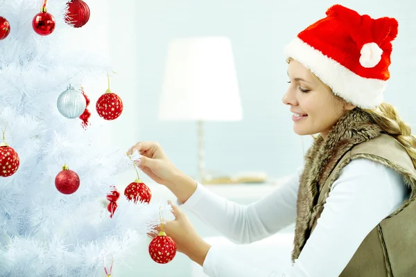 Woman hanging Christmas balls on a tree — Stockfoto