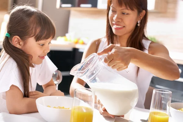 Mãe derramando leite no prato de sua filha — Fotografia de Stock