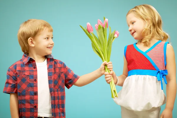 Chłopiec dając kwiaty do całkiem mała dziewczynka — Zdjęcie stockowe
