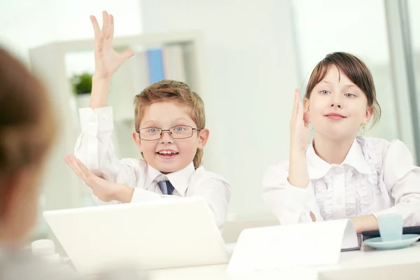 Förskolebarn att höja händerna i klassrummet — Stockfoto