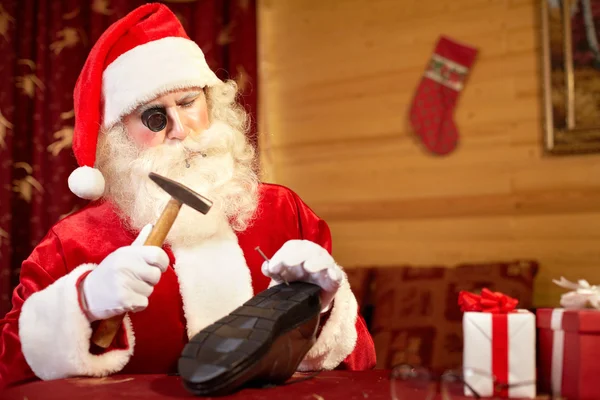 Santa Claus repairing shoe in workshop — ストック写真