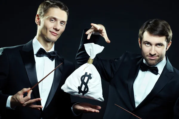 Magicians doing tricks with sack of money — Stock Photo, Image