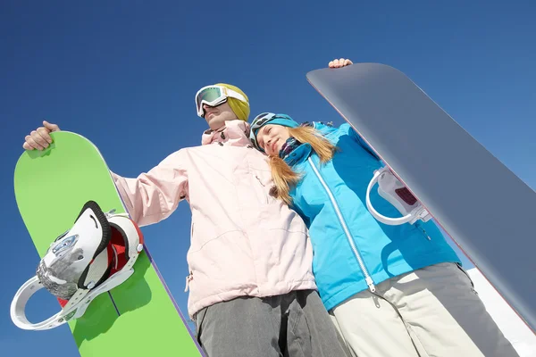 Pareja con tablas de snowboard y abrazándose — Foto de Stock