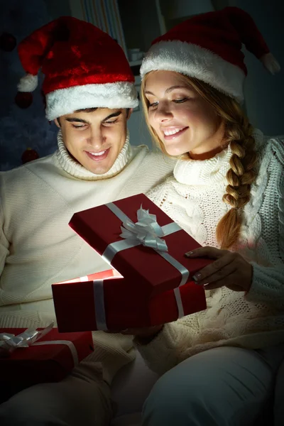 Pareja joven abriendo una caja de regalo brillante — Foto de Stock