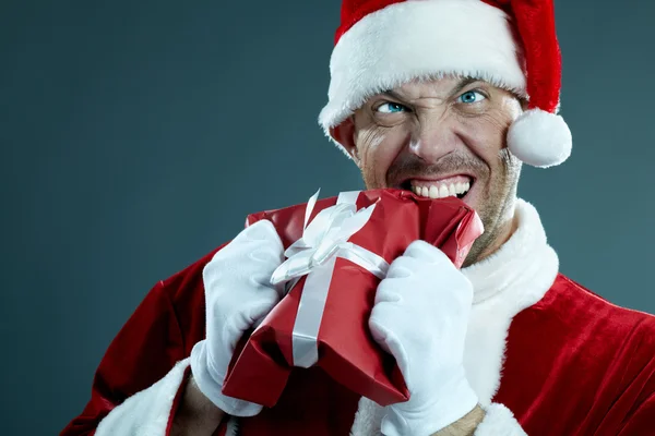 Agresivo Santa Claus mordiendo una caja de regalo — Foto de Stock