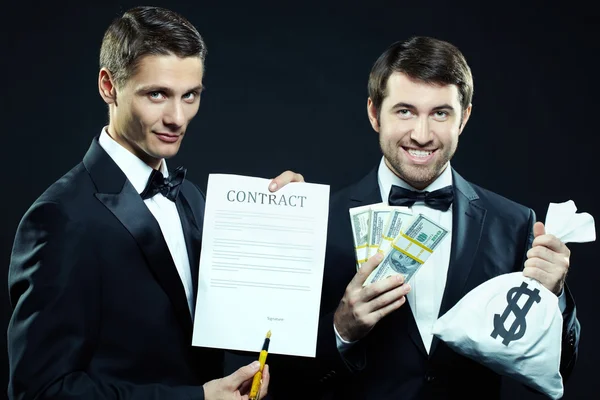 Homens apresentáveis mostrando contrato e dinheiro — Fotografia de Stock