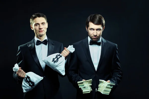 Men in tuxedos offering money — Stock Photo, Image