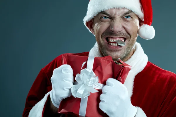 Loco Santa Claus masticando una caja de regalo — Foto de Stock