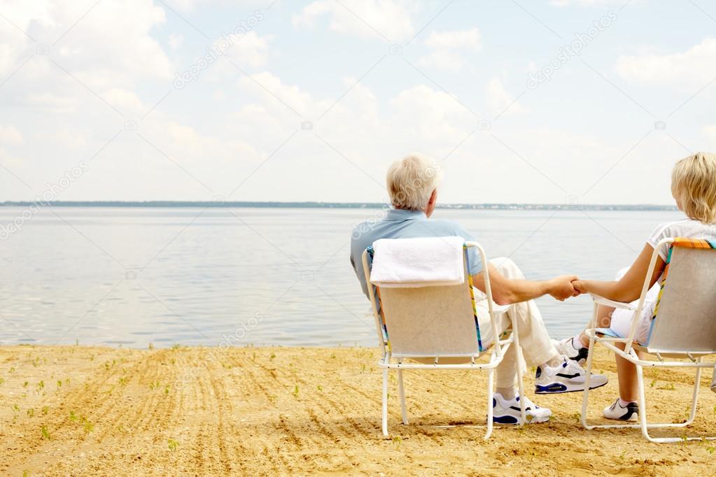 mature couple resting in chaise lounges 