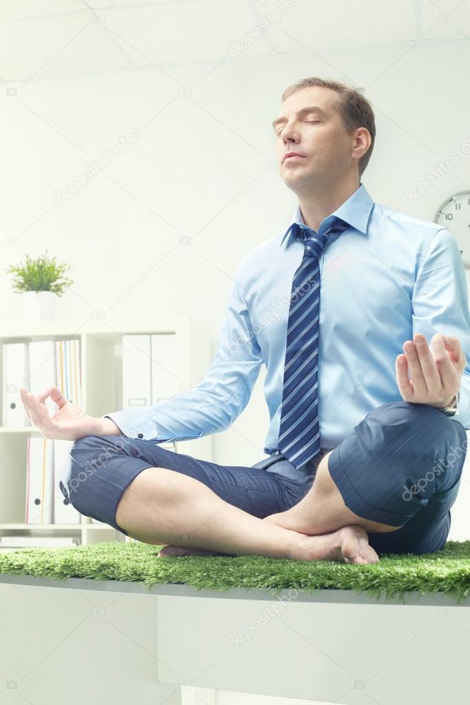 Businessman meditating in lotus position 