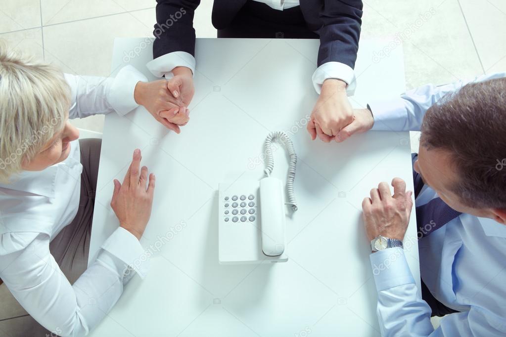 Colleagues holding by hands and looking at telephone