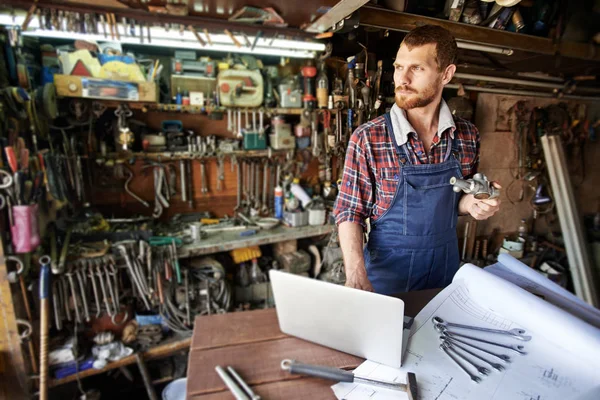 Junger Mechaniker prüft technisches Teil — Stockfoto