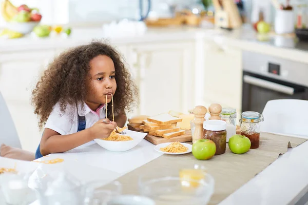 Kleines Mädchen isst Spaghetti in der Küche — Stockfoto