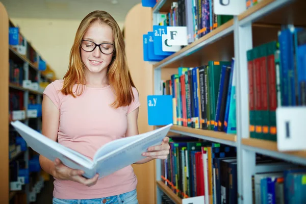 Linda chica leyendo libro en la biblioteca — Foto de Stock